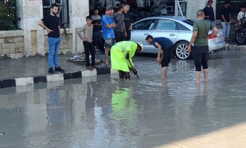 عنصر من الدفاع المدني السوري إلى جانب أهالِ يقومون بتصريف مياه الأمطار بحلب- 1 تشرين الأول 2026 (الدفاع المدني السوري)