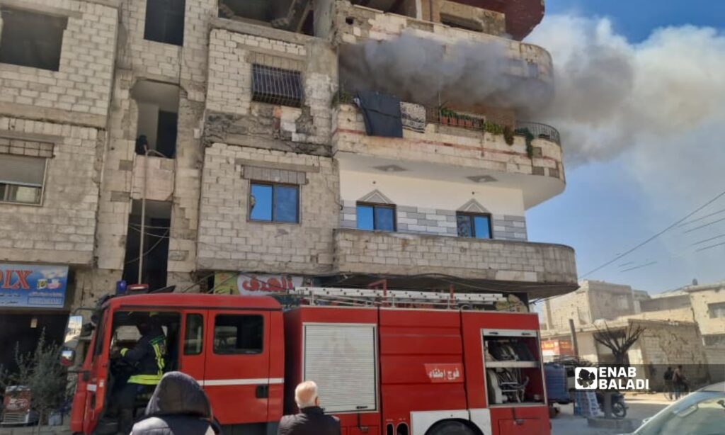 إطفائي من الدفاع المدني يرش المياه باتجاه شقة سكنية تصاعد منها الدخان في بناء قرب جامع الفارس بمدينة داريا