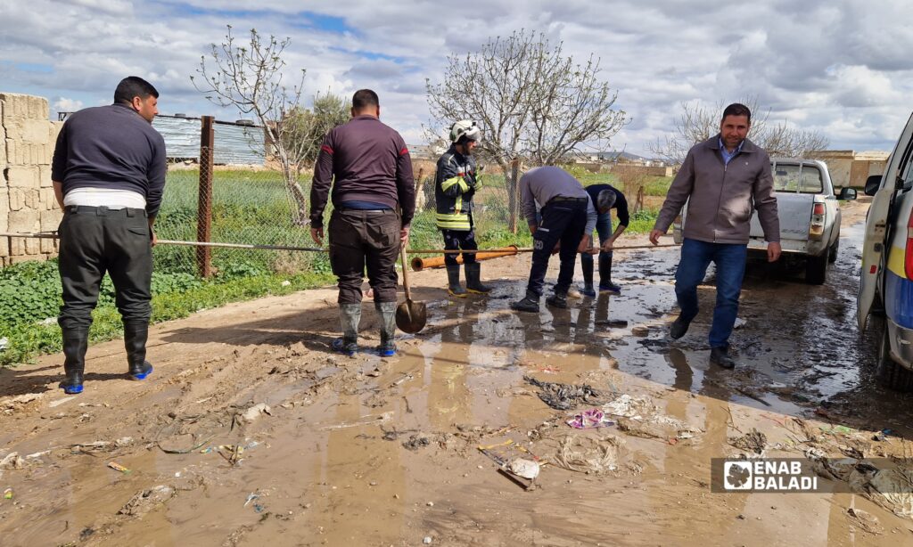 فرق الدفاع المدني وأهالٍ يفتحون مجرى لتصريف المياه بعد فيضان ناتج عن تعديات على مجاري الري في داريا
