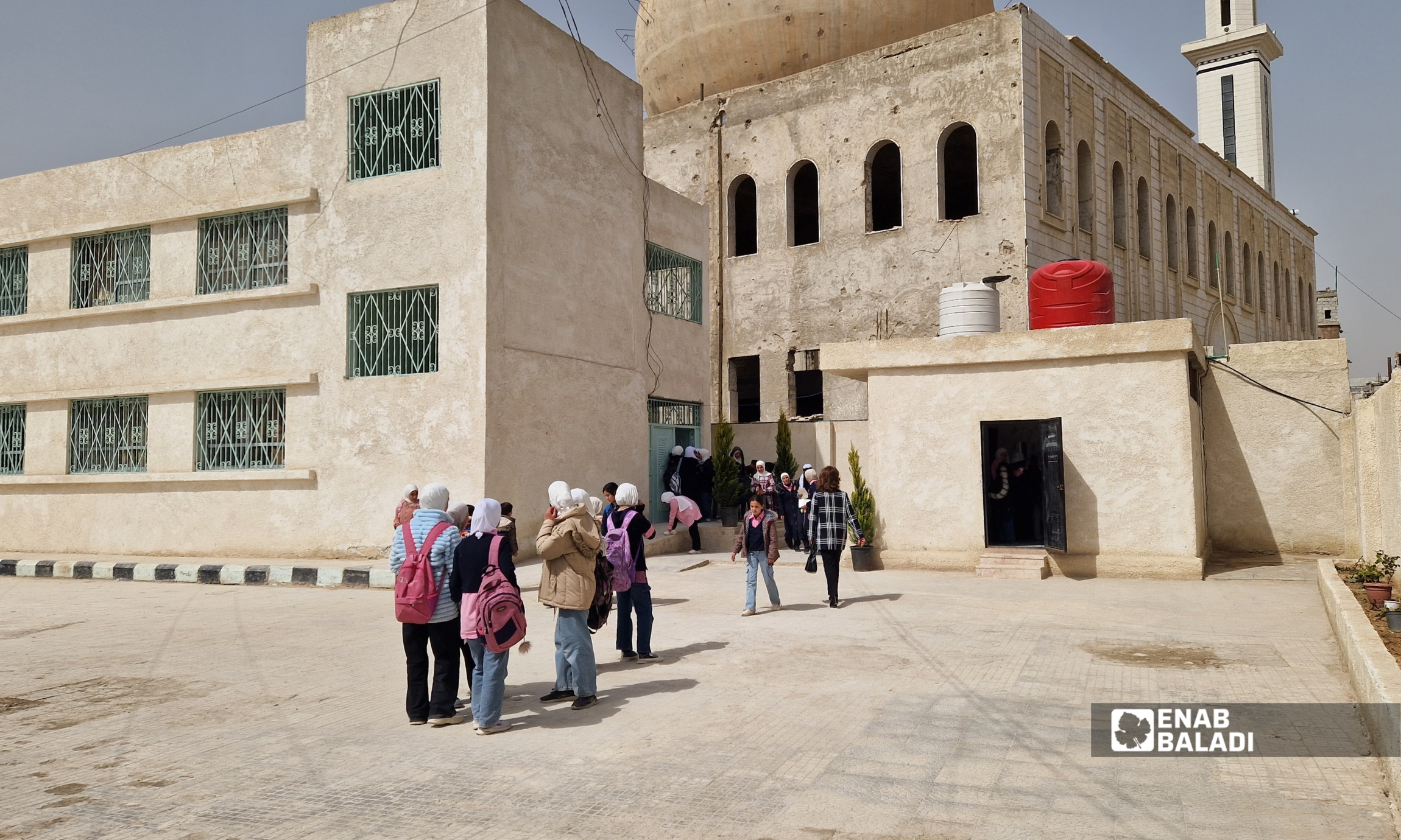 لطيفة الدروبي تزرع شجرة زيتون في باحة مدرسة “الإبداع للبنات” في داريا خلال زيارتها - 12 آذار 2026 (عنب بلدي - سعيد خشفة)