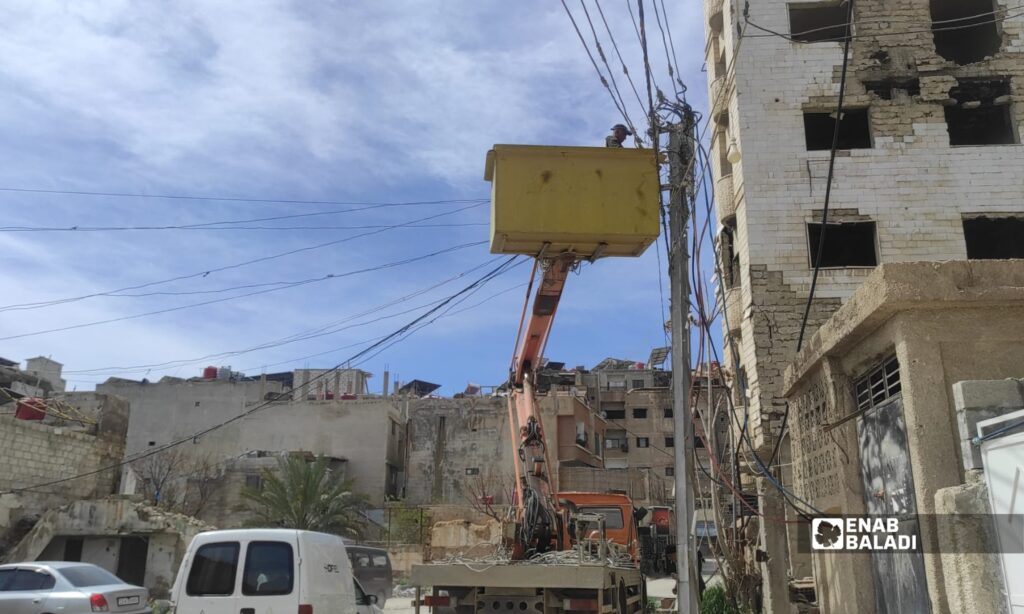 ورشة كهرباء تعمل على إصلاح عطل في الشبكة باستخدام رافعة خلف المخفر في مدينة داريا