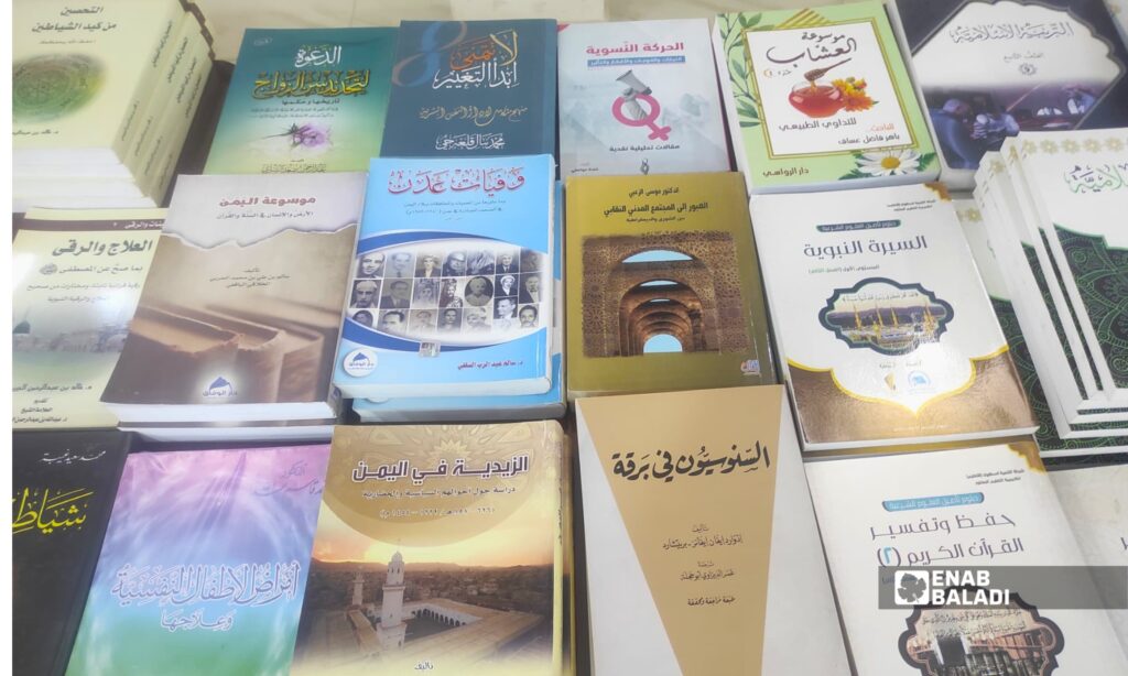 طلاب وزوار يتصفحون كتبًا ضمن معرض الكتاب في المركز الثقافي بمدينة داري