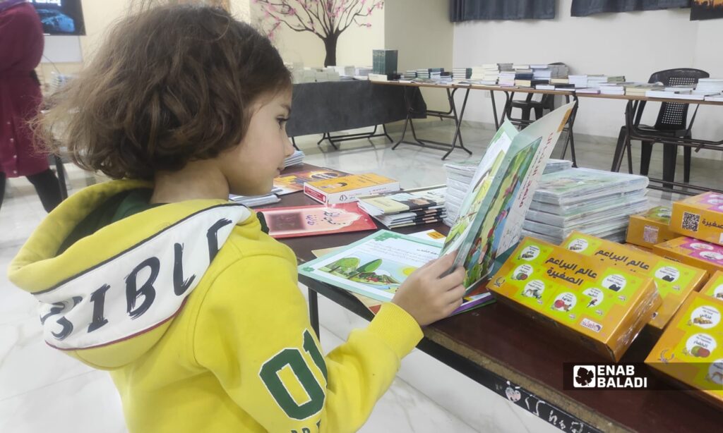 طلاب وزوار يتصفحون كتبًا ضمن معرض الكتاب في المركز الثقافي بمدينة داري