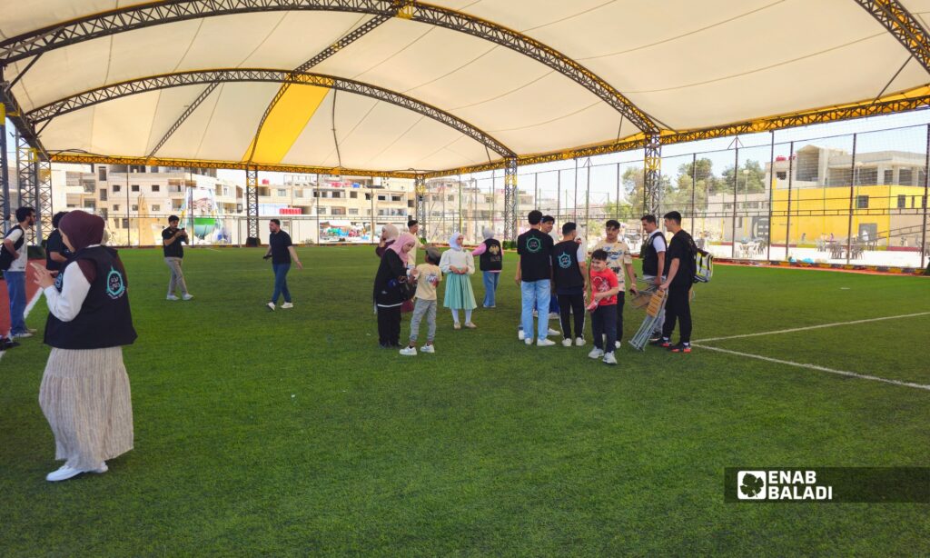 أطفال ومتطوعون خلال فعالية “الحافلة الثقافية” في ملعب داريا 