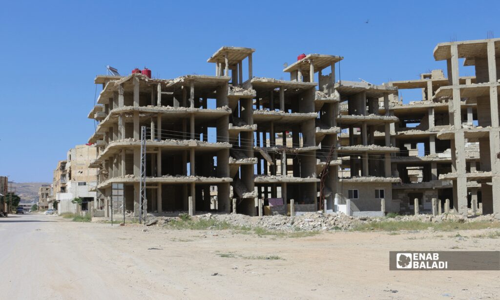 أبنية مدمرة وردم على جانبي طريق في مدينة داريا