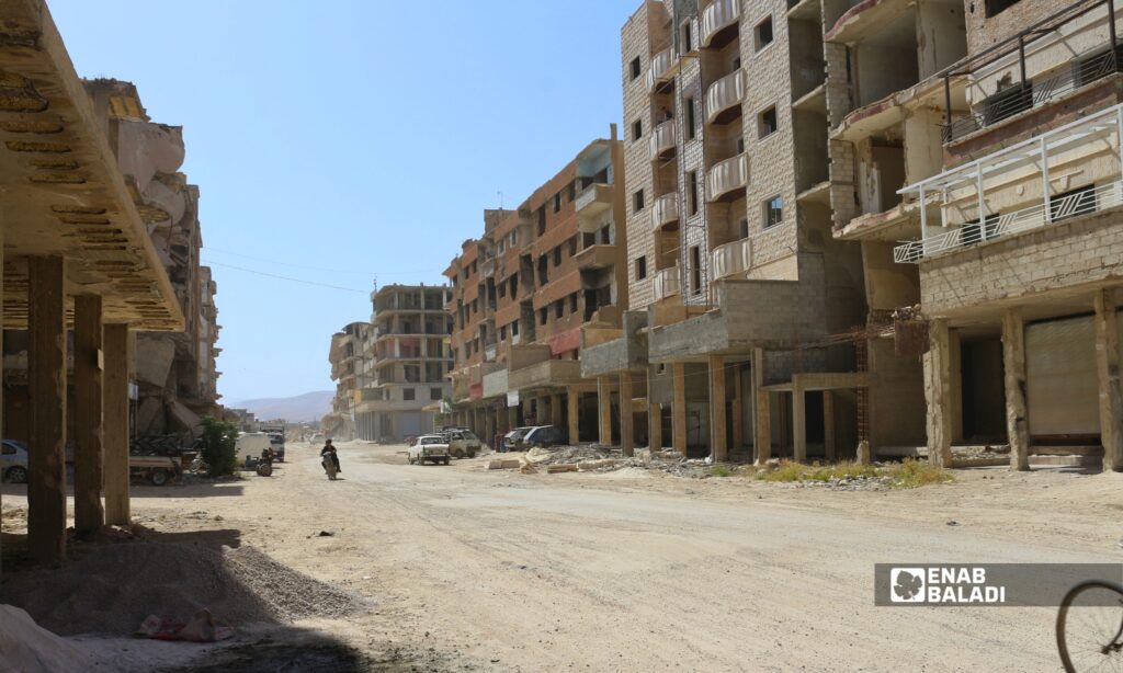 أبنية مدمرة وردم على جانبي طريق في مدينة داريا