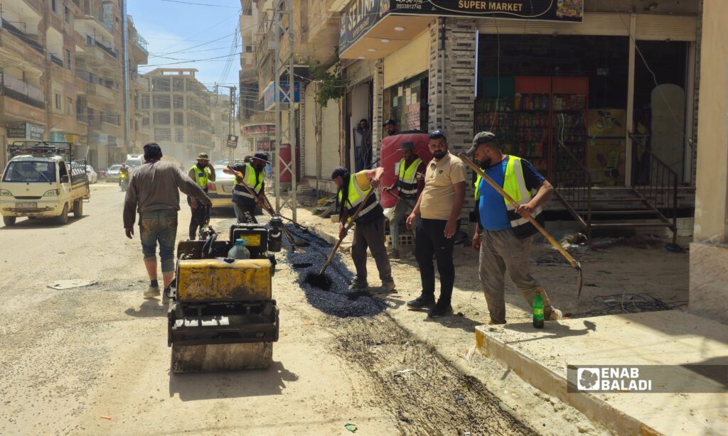 عمال يزفتون أحد المقاطع المحفورة في شارع الوحدة بمدينة داريا