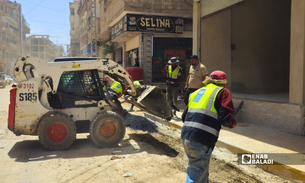 عمال يزفتون أحد المقاطع المحفورة في شارع الوحدة بمدينة داريا