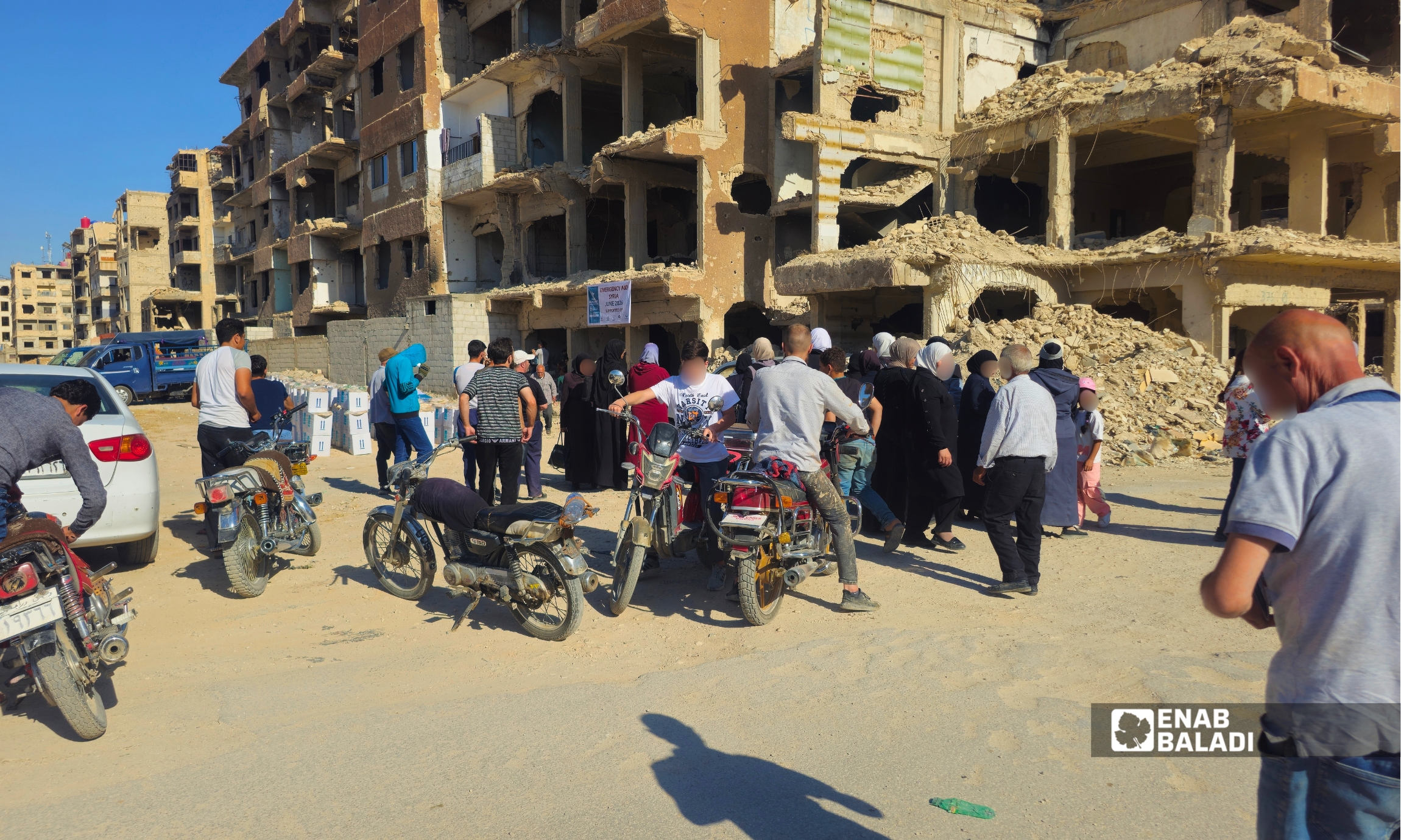 مستفيدون ينتظرون توزيع مساعدات غذائية في منطقة الجمعيات بمدينة داريا
