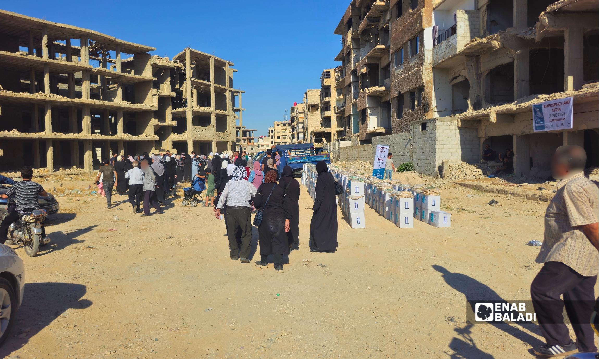 مستفيدون ينتظرون توزيع مساعدات غذائية في منطقة الجمعيات بمدينة داريا