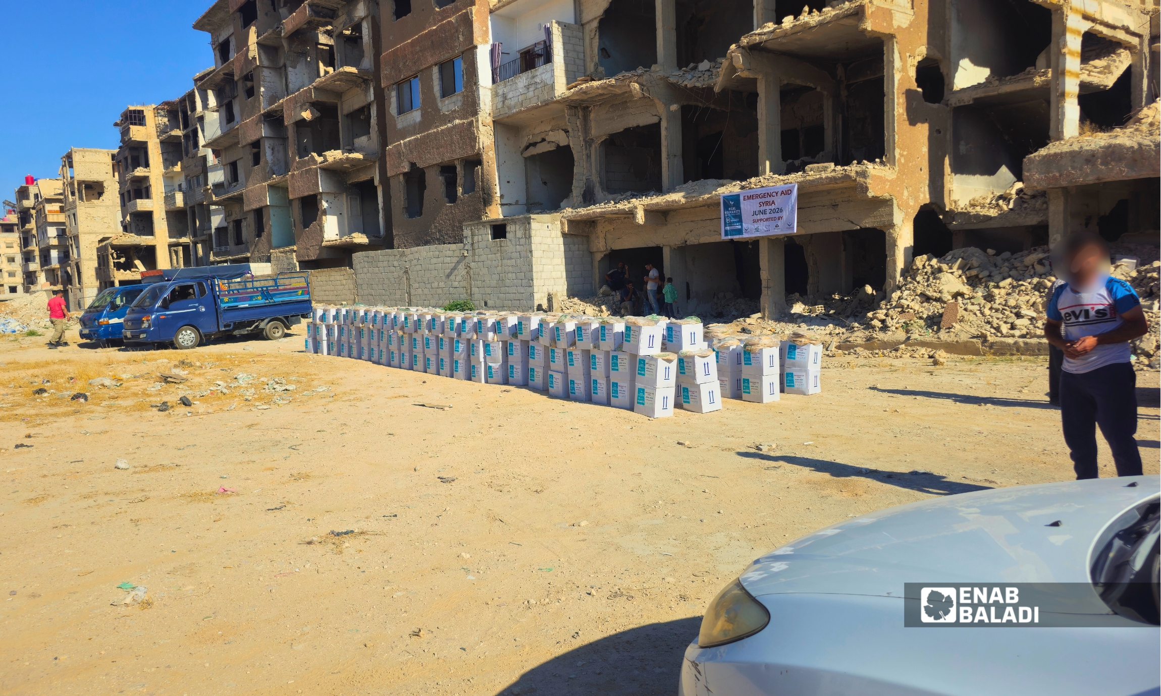 مستفيدون ينتظرون توزيع مساعدات غذائية في منطقة الجمعيات بمدينة داريا