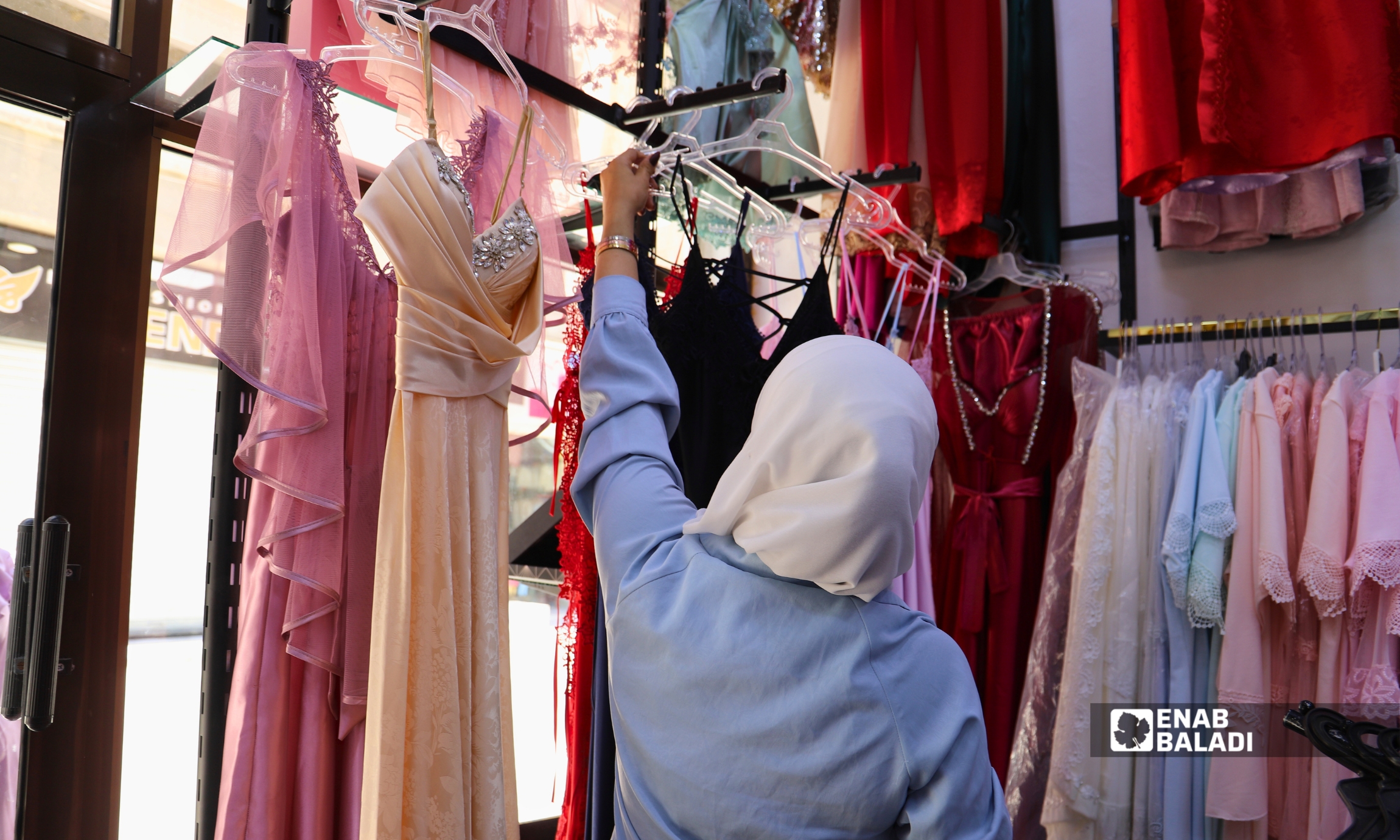 امرأة عاملة ترتب الملابس في أحد محال مدينة داريا