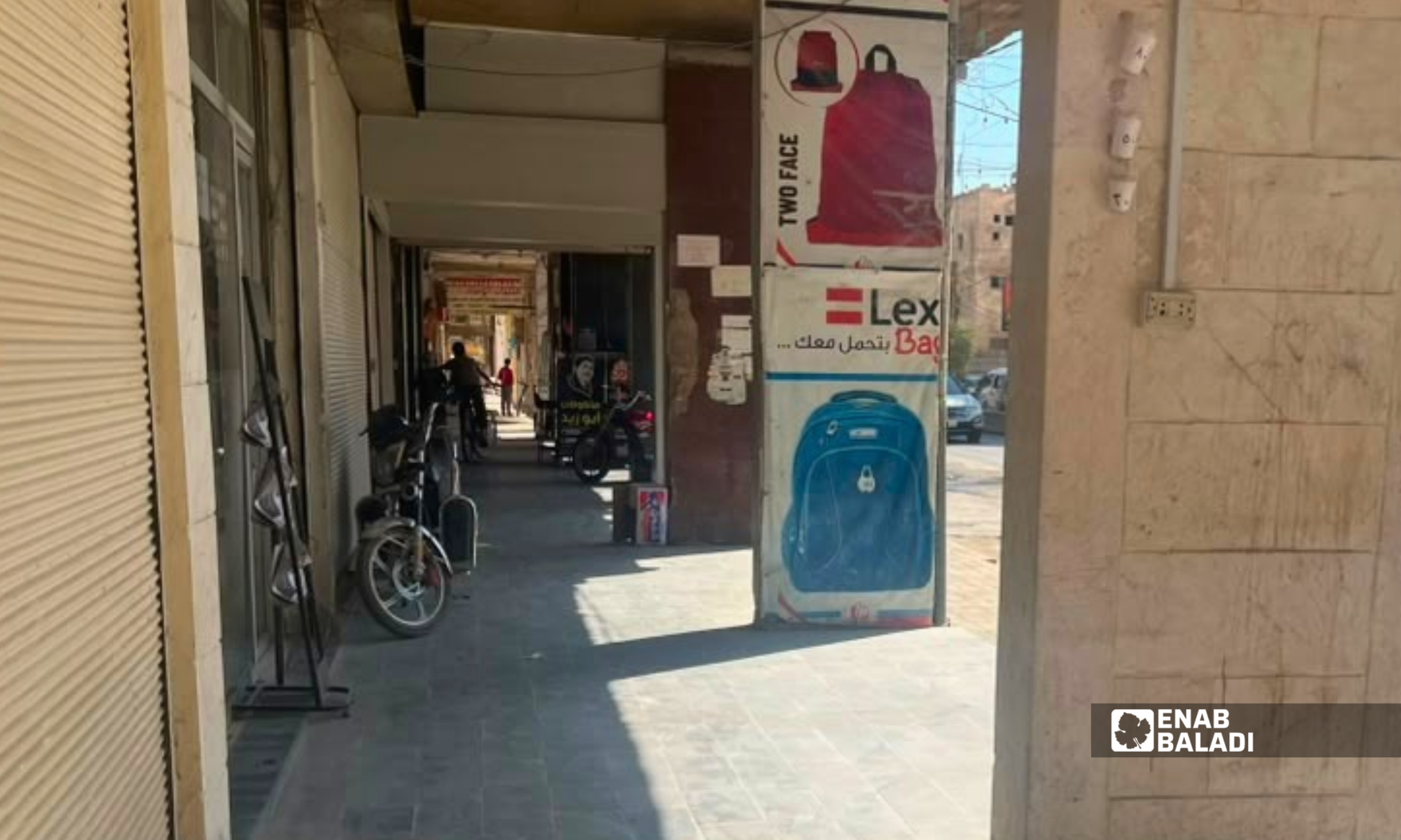دراجات نارية مركونة على رصيف أمام محال تجارية في مدينة داريا