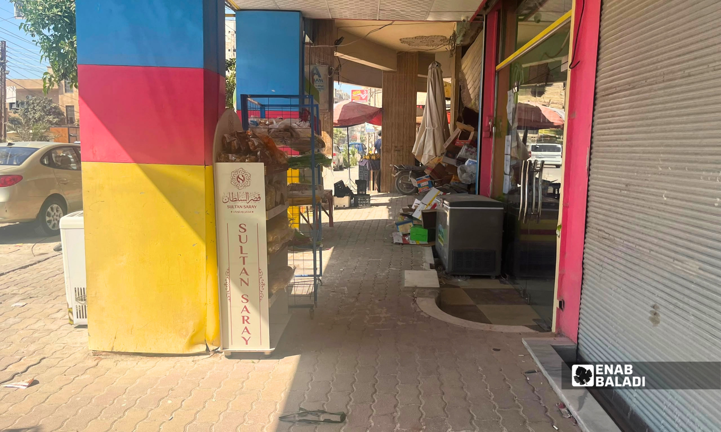 بضائع معروضة على رصيف أمام محال تجارية في مدينة داريا