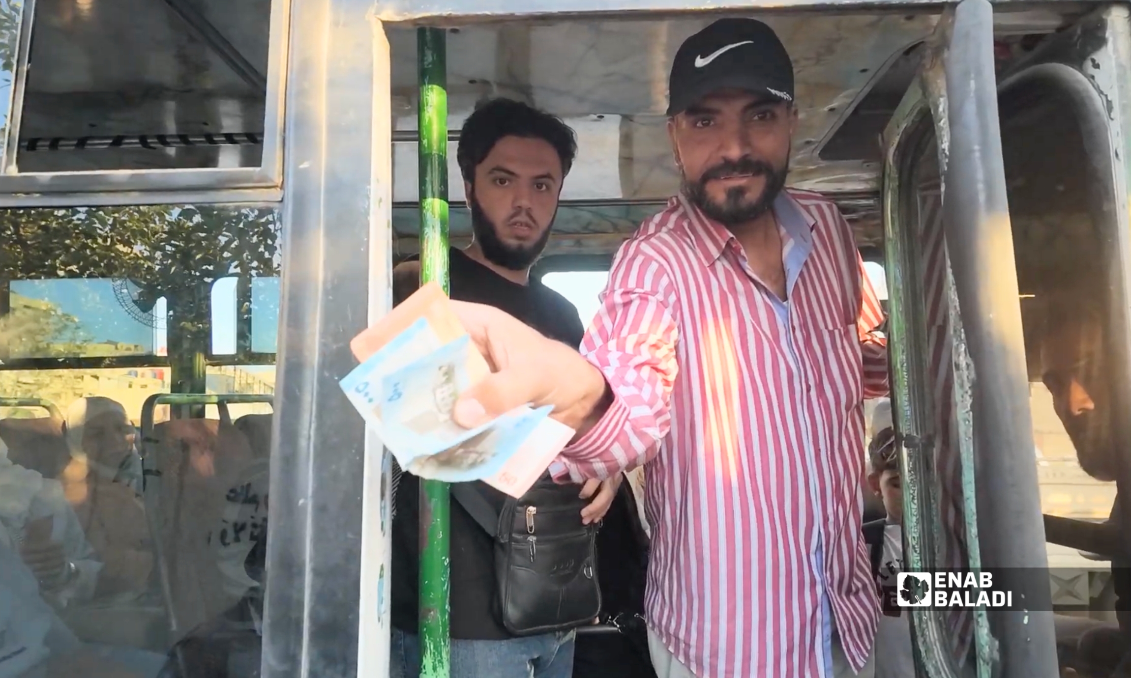 سائق سرفيس يعد أوراقًا نقدية داخل مركبته في مدينة داريا