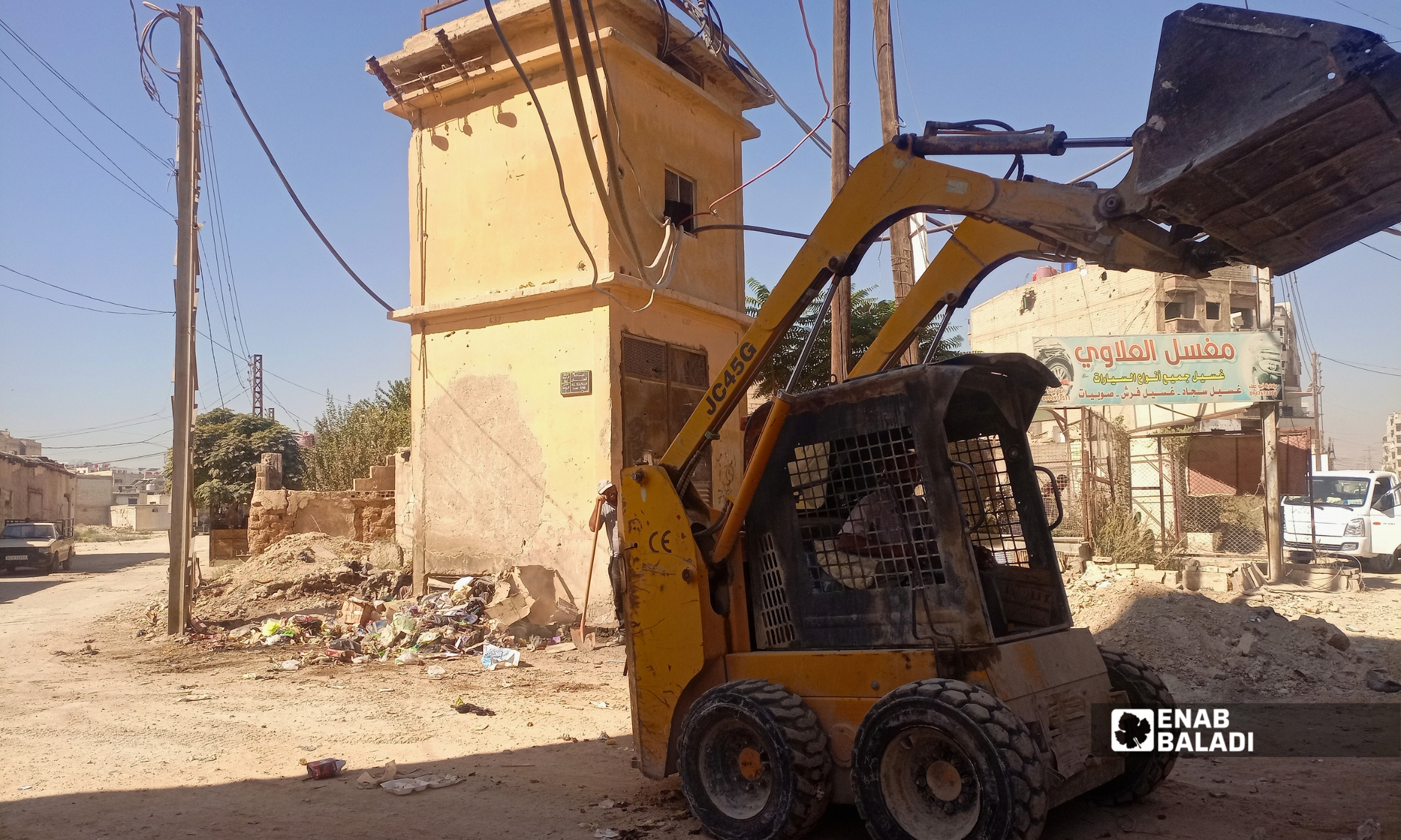 عمال النظافة يرفعون كومة من النفايات في أحد شوارع داريا