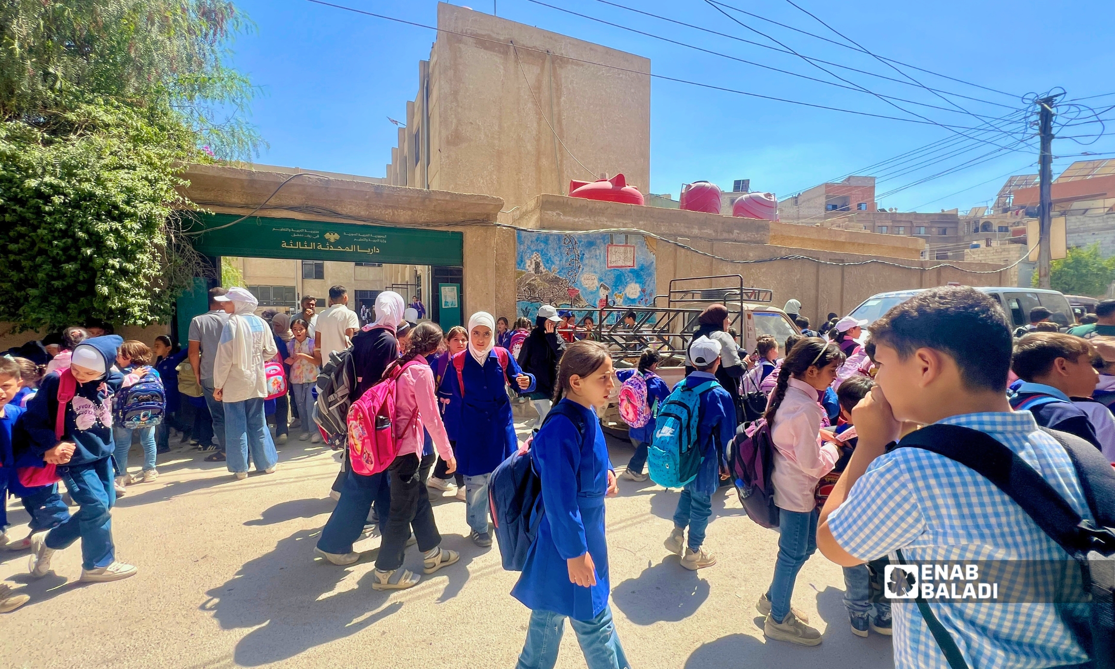 طلاب وأهالٍ أمام مدرسة داريا المحدثة الثالثة في مدينة داريا