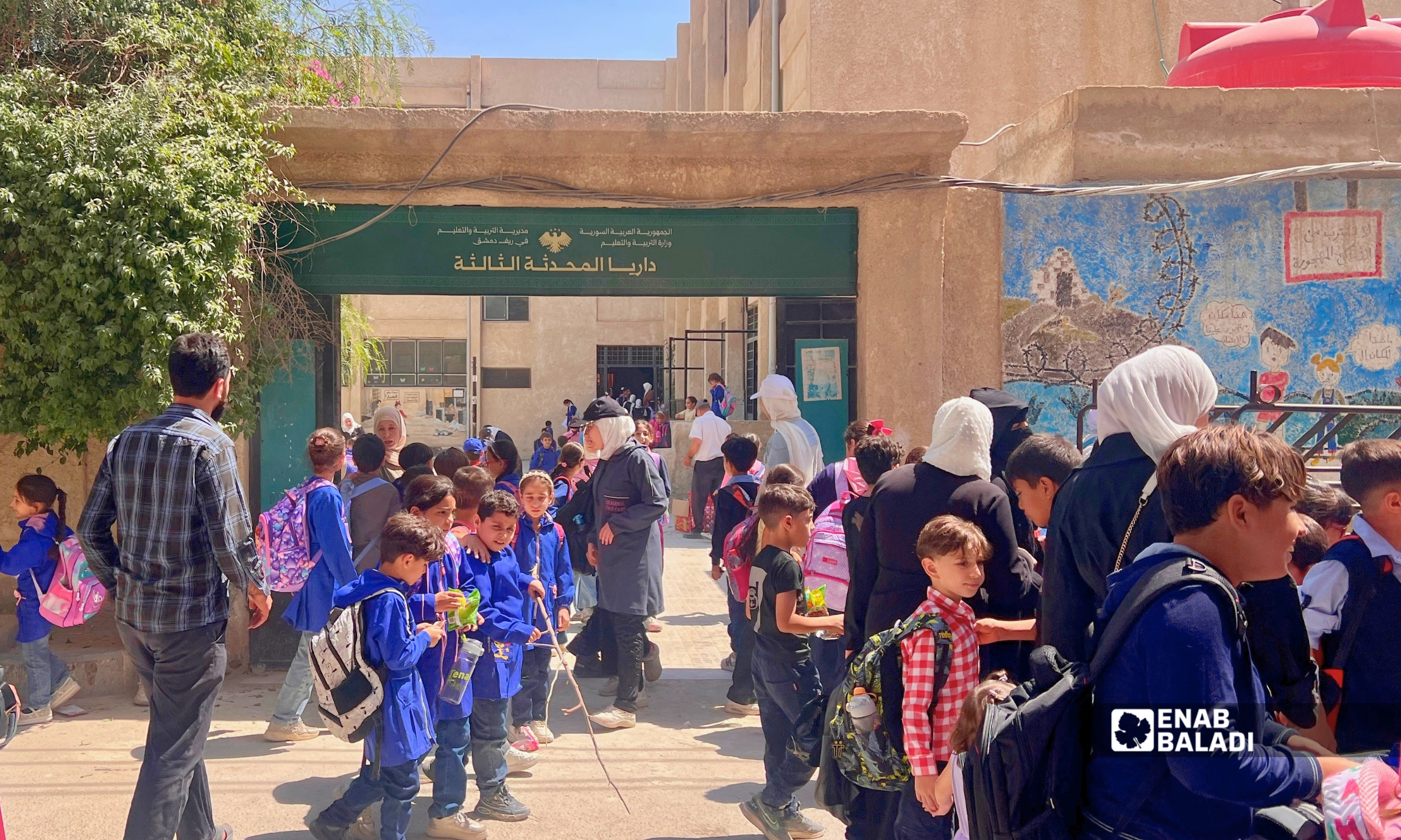 طلاب وأهالٍ أمام مدرسة داريا المحدثة الثالثة في مدينة داريا