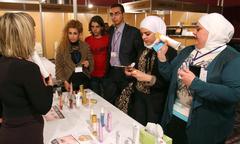 Syrian women examining beauty products at the first specialist beauty exhibition in Damascus, 7 December 2014 (AFP)