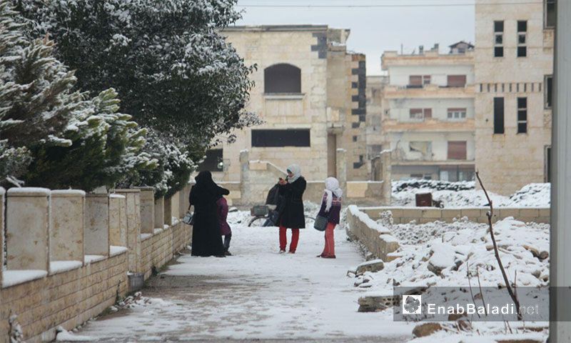 Women in the besieged al-Waer neighborhood during snowfall, 28 January 2017 (Enab Baladi)