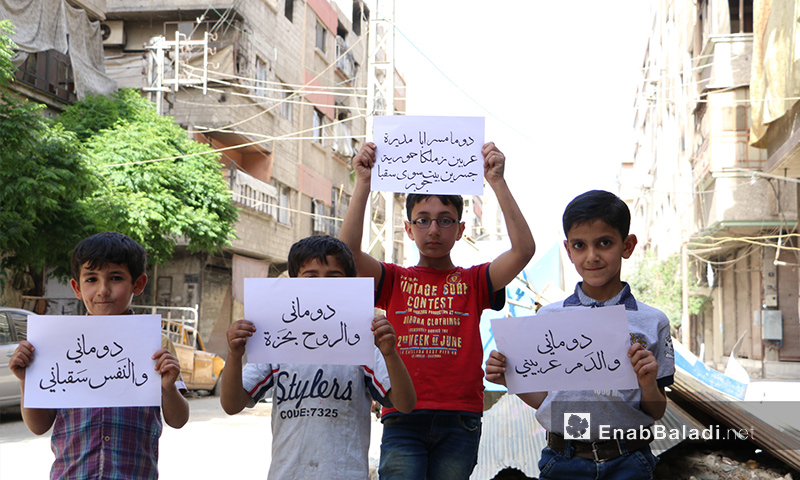 Children from Duma holding signboards that express the unity among cities and towns in Ghouta – April 11, 2017 (Enab Baladi)