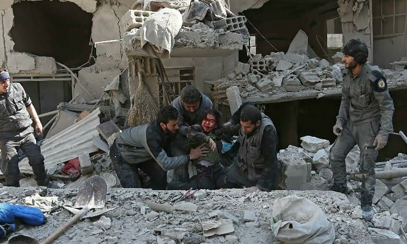 Civil Defense members helping an injured child in Hamouriyah city - 21 February 2018 (AFP)
