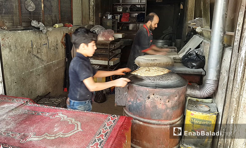 A child helping his father in baking bread in Eastern Ghouta – April 2017 (Enab Baladi)