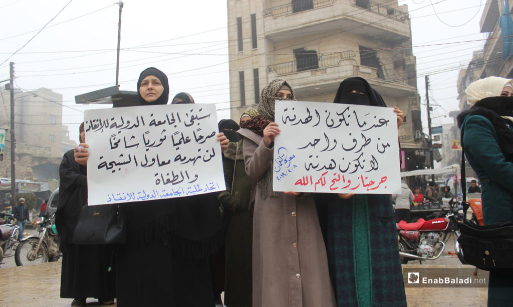A demonstration in the city of Maarrat al-Nu'man protesting the decision of closing the International Rescue university in Idlib [From left to right the signs say: The International Rescue University will Remain an lofty Educational and Rebellious Edifice, which Tools of Thugs and Tyrants Would not Dare Destroy (Students Union of the International Rescue University). A One-side truce is Not a Truce (Jarjanaz and al-Tah, God Is There for You!)]– February 8, 2019 (Enab Baladi)