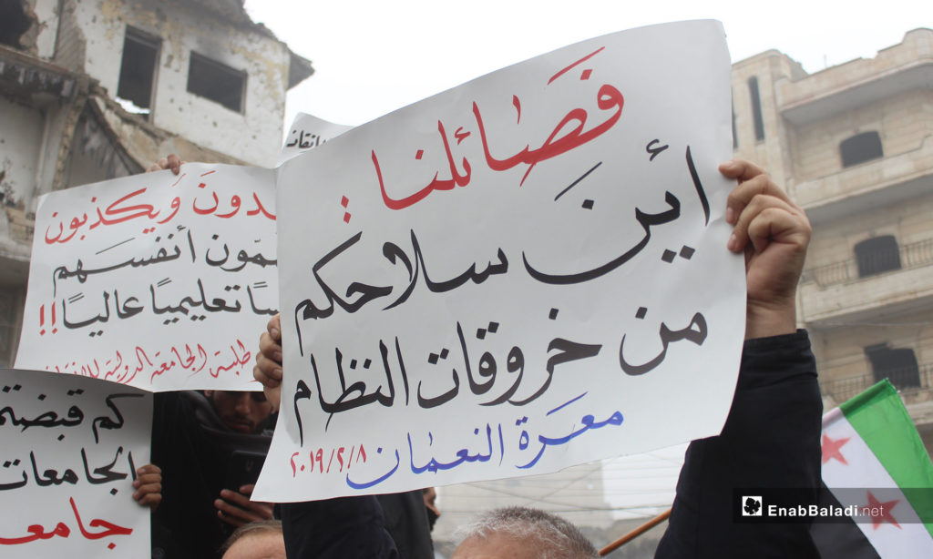 A demonstration in the city of Maarrat al-Nu'man protesting the decision of closing the International Rescue university in Idlib [The sign says: Our Factions, What Are You Weapons Doing about the Regime’s Violations; Maarrat al-Nu'man.]- February 8, 2019 (Enab Baladi)