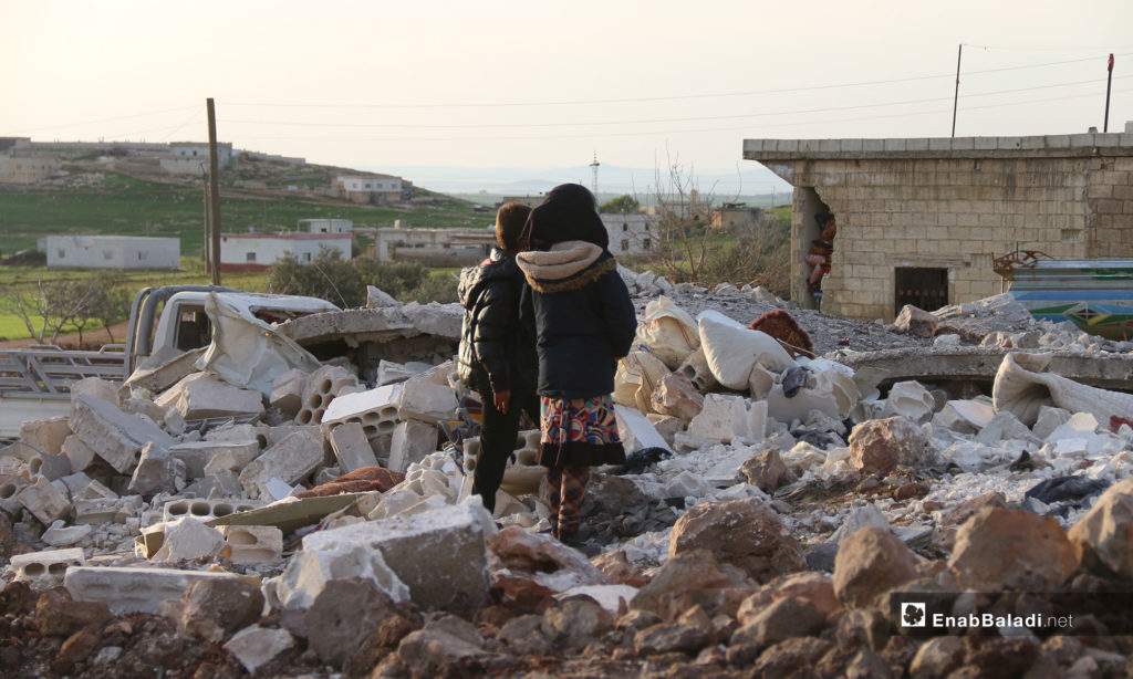 Two children looking at the rubble of houses after the Russian aircraft shelling of the town of Faqie, southern Idlib - March 21, 2019 (Enab Baladi)