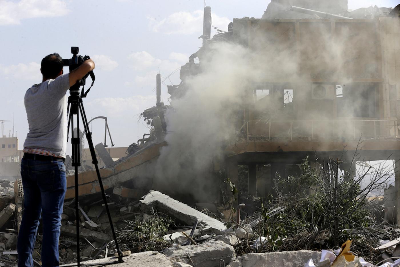 Journalist photographing wreckage of a destroyed building at the Scientific Studies and Research Center in Barza, north of Damascus - 2018 (AFP)