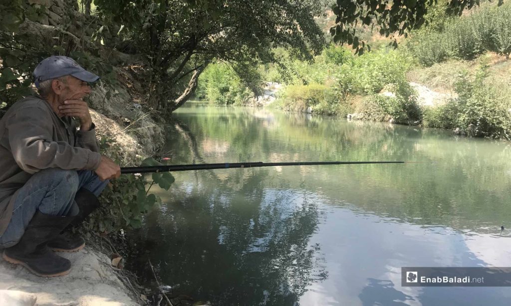 A man fishing in the Assi River, near the city of Darkoush, western rural Idlib -September 8, 2019 (Enab Baladi)