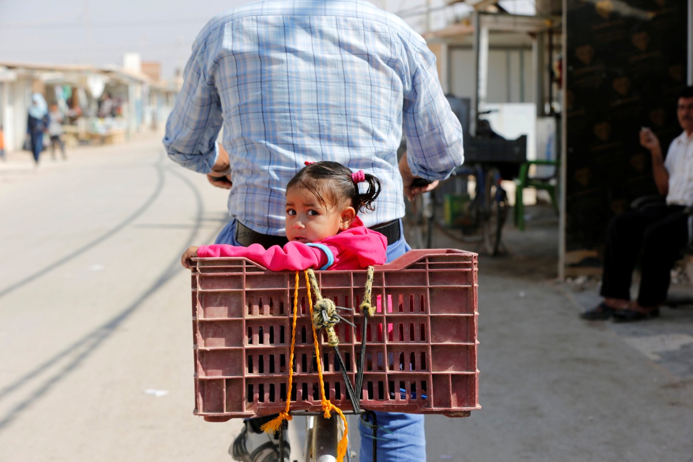Syrian refugee riding a bicycle with his daughter in the main market, Zaatari refugee camp in the Jordanian city of Mafraq - 2016 (Reuters)