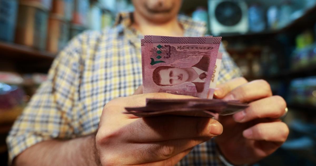 A trader in Damascus carrying a 2,000 Syrian pound banknote - 2019 (AFP)