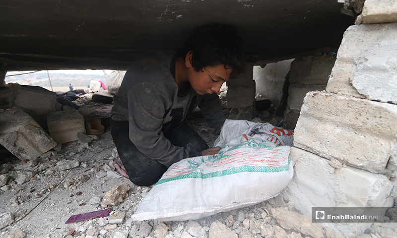 A child scavenges what he can from the debris of his home in the town of Kafr Taal in the western countryside of Aleppo - 20 January 2020 (Enab Baladi)
