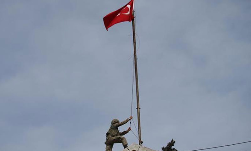 A Turkish soldier raises his country's flag in the city of Afrin in northern Syria (Anadolu)