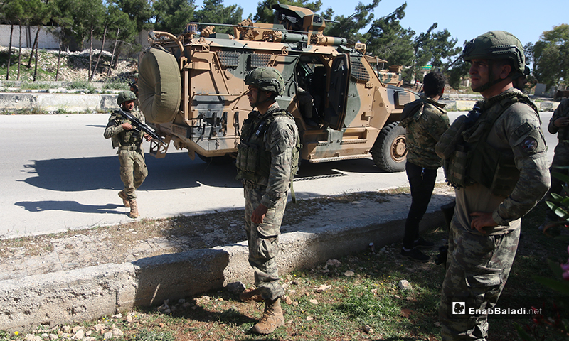 Members of the Turkish Army Forces (TAF) standing near a military vehicle while being deployed on the Aleppo – Lattakia international “M4” highway during the eleventh Russian-Turkish joint patrol – 14 May 2020 (Enab Baladi)