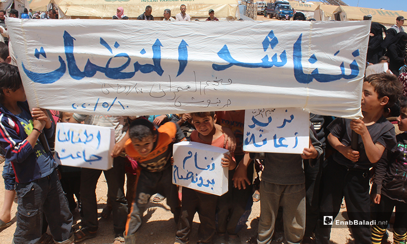 Banners raised in the demonstration that took place near the al-Omran camp, west of Haranabush, demanding to ensure basic needs and services - 10 May (Enab Baladi)
