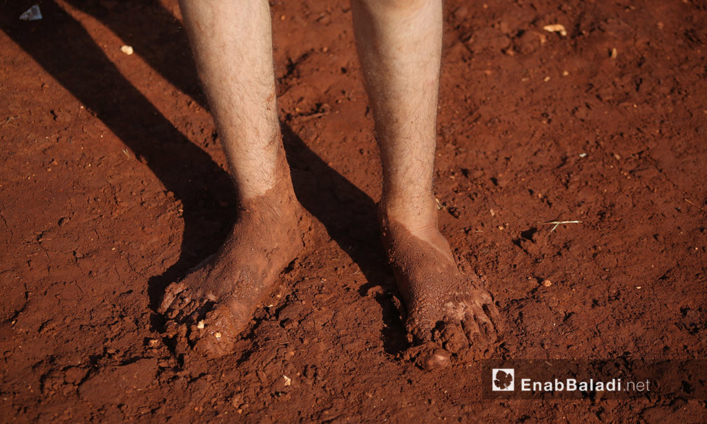 A child’s two feet covered with mud after the rainstorm that hit “Sahl al-Khair” camp for Syrian internally displaced people (IDPs) near Kafr Bunni in northern Idlib countryside – 19 June 2020 (Enab Baladi / Yousef Ghuraibi)