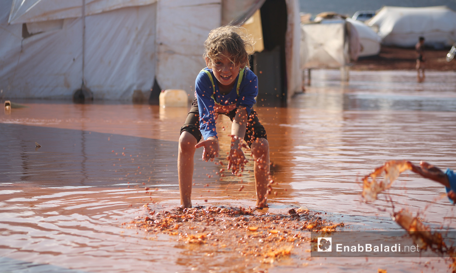 A child playing amid the stormwater at “Sahl al-Khair” camp for Syrian internally displaced people (IDPs) after the rainstorm near Kafr Bunni in northern Idlib countryside – 19 June 2020  (Enab Baladi / Yousef Ghuraibi)
