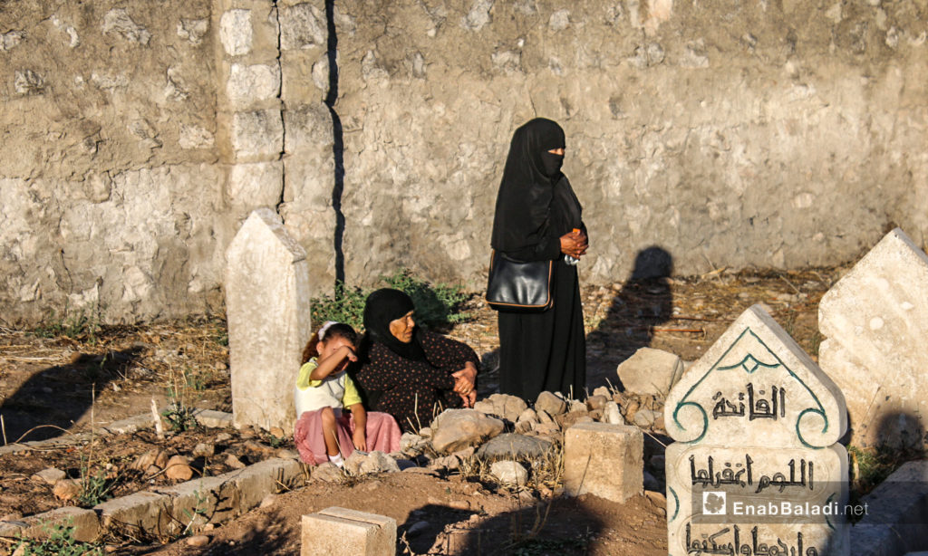 A woman visiting the grave of one of her family members in Dabiq town in northern Aleppo countryside – 31 July 2020 (Enab Baladi / Abdul Salam Majan)