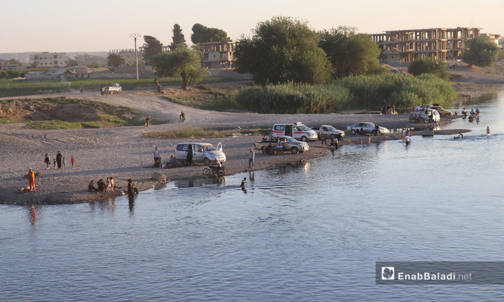 People sitting on one of the Euphrates River banks in al-Raqqa province – 24 July 2020 (Enab Baladi / Abdul Aziz Saleh)