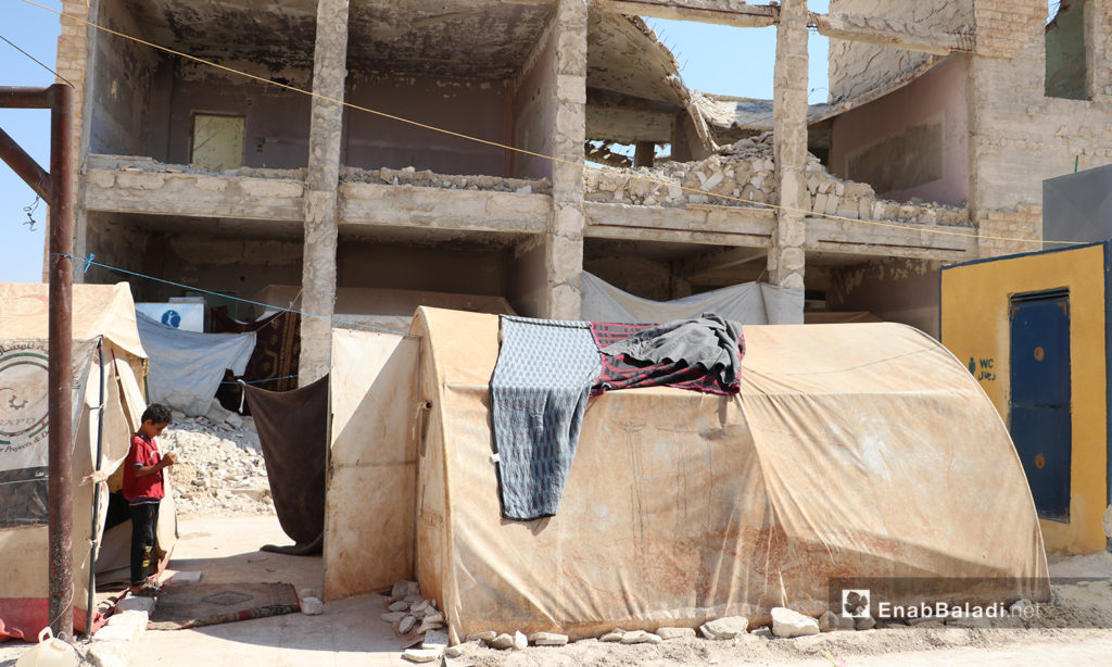 A makeshift tent set in front of a destroyed building in Qibtan Camp for internally displaced people (IDPs) near Akhtarin town in northern Aleppo countryside – 17 July 2020 (Enab Baladi / Asim Melhem)