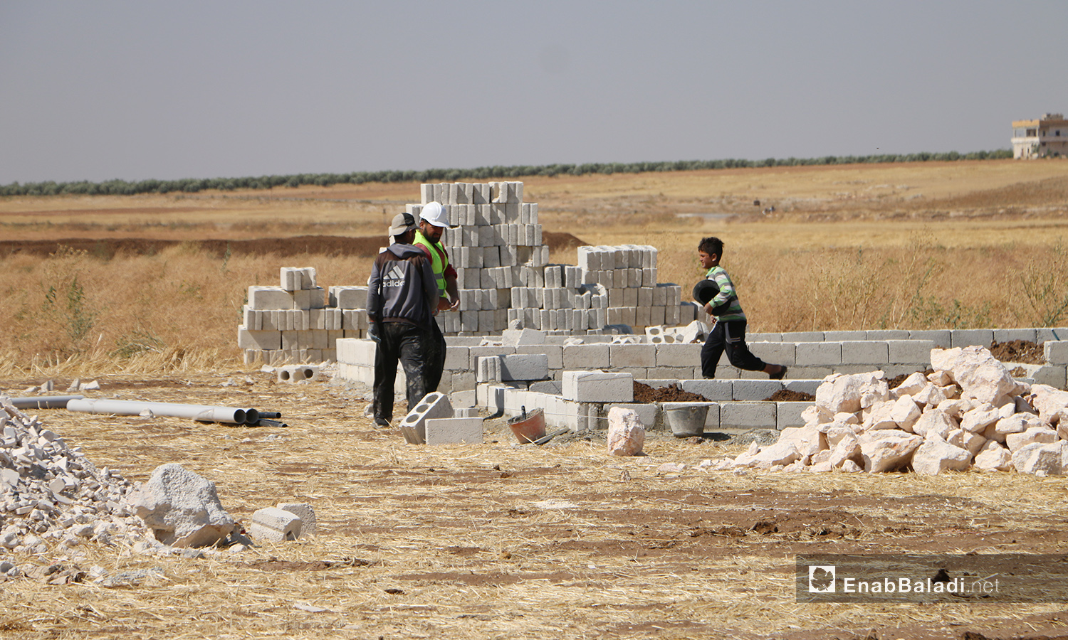 The construction workers of the concrete housing units project to replace the makeshift tents. This project is conducted by humanitarian organizations and bodies operating in northern Syria in Bahorta village of northern Aleppo countryside – 26 June 2020 (Enab Baladi / Abdul Salam Majan)