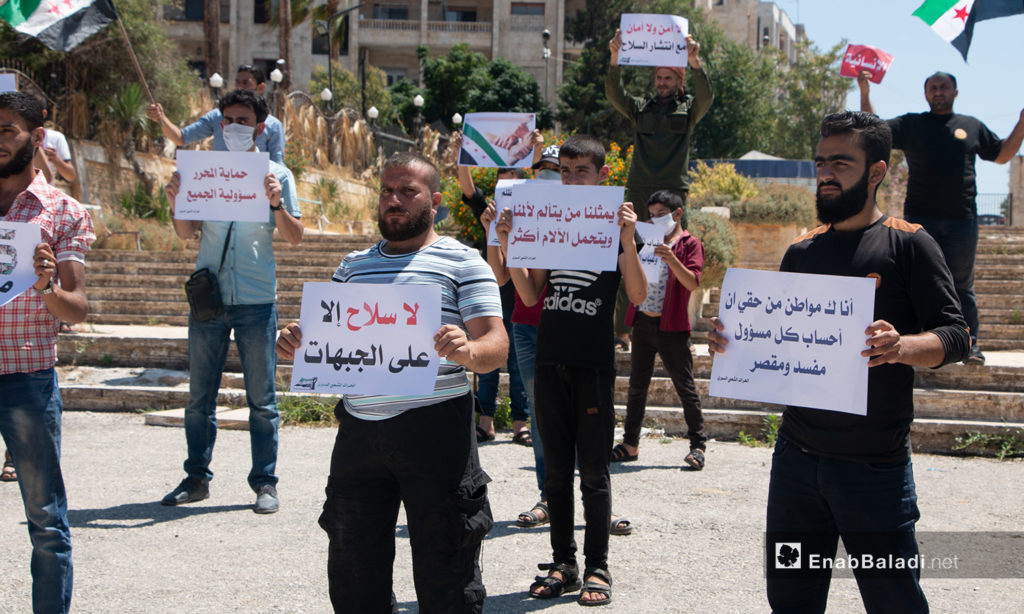 A group of young men carrying signs during a protest stand in Idlib city – 17 July 2020 (Enab Baladi / Anas al-Khouli)
