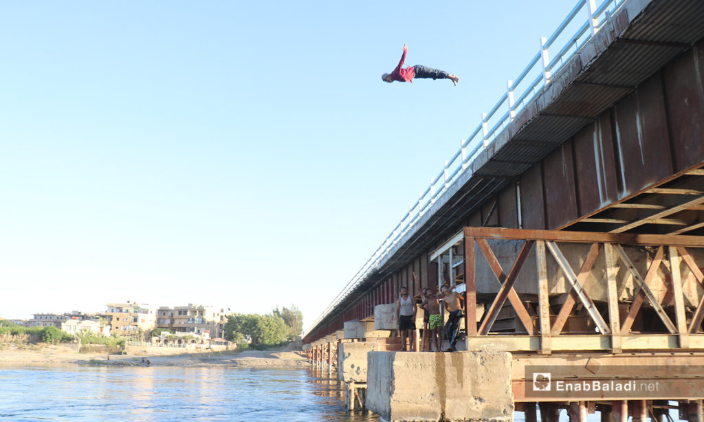 A young man jumping from the top of a bridge over the Euphrates River in al-Raqqa province – 24 July 2020 (Enab Baladi / Abdul Aziz Saleh)