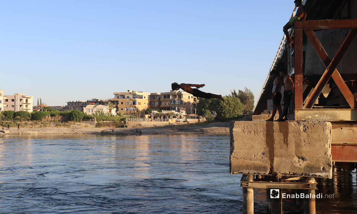 A young man jumping from the top of a bridge over the Euphrates River in al-Raqqa province – 24 July 2020 (Enab Baladi / Abdul Aziz Saleh)