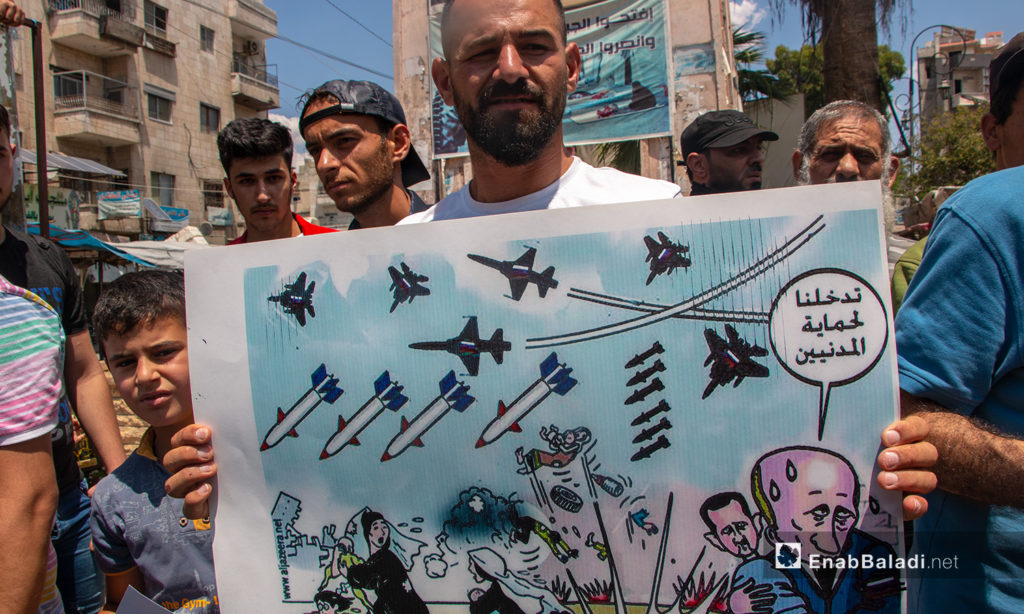 A man carrying a sign about the targeting of Syrian civilians by the Russian warplanes and missiles – 03 July 2020 (Enab Baladi / Anas al-Khouli)
