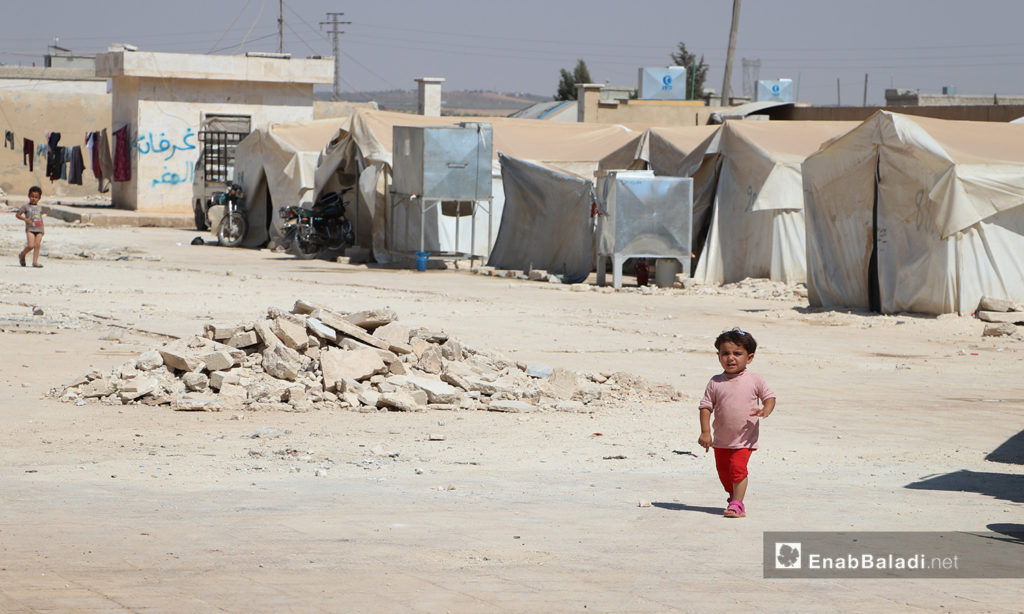 A child walking alone under the sun in Qibtan Camp for internally displaced people (IDPs) near Akhtarin town in northern Aleppo countryside – 17 July 2020 (Enab Baladi / Asim Melhem)