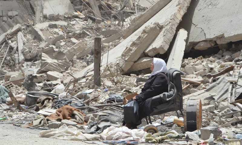 A Syrian woman sitting on the rubble of the Yarmouk Camp - 2018 (Yarmouk Camp News)